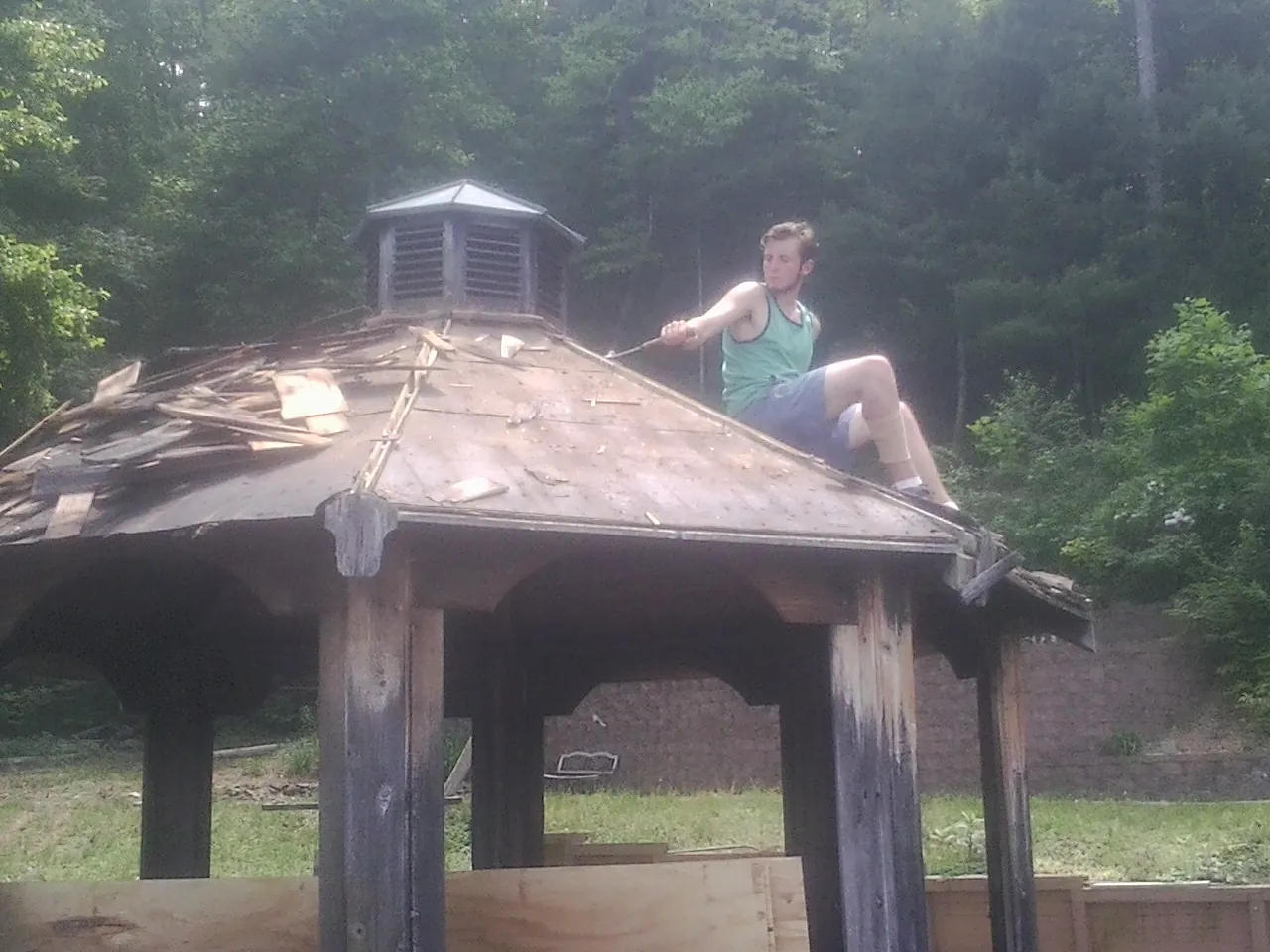 Tearing the old roof off a wooden gazebo before new shakes in Great River