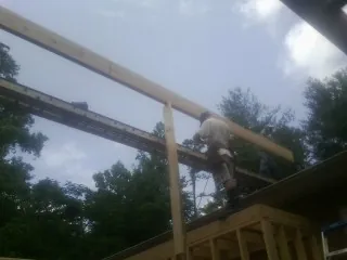 Carpenter setting a ridge beam over a new addition frame — Ice Dam Removal by Roofing Brothers in Great River