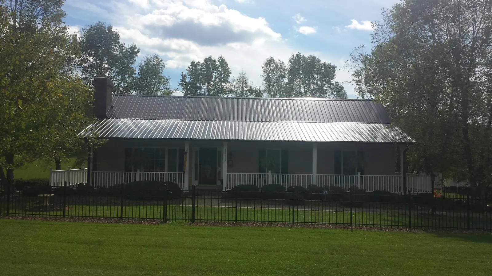 Gray metal roof on a brick ranch with a full width front porch — Gutter Guard Installation work by our crew in Great River