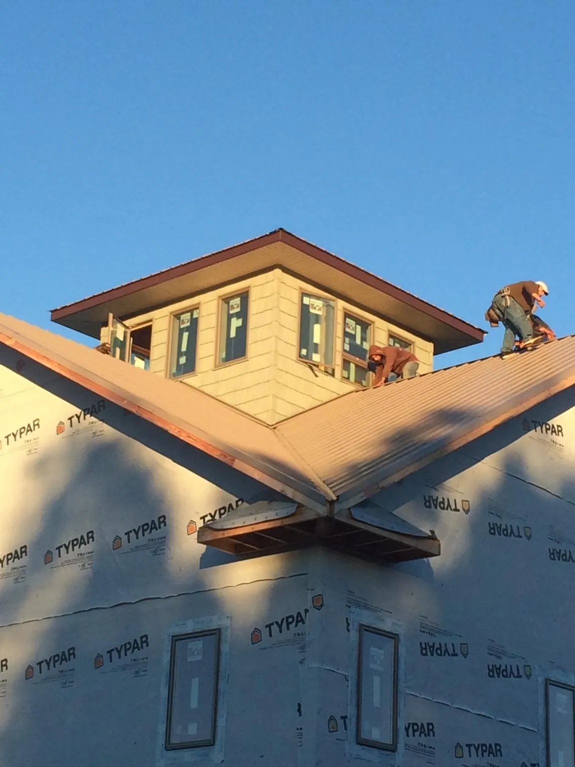 Roofers working around a rooftop cupola on a new metal roof at sunset — Roof Waterproofing in Great River by Roofing Brothers
